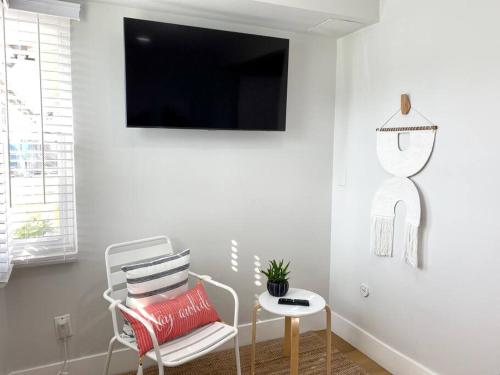 a white living room with a chair and a tv at Steps To The Beach, Main Street and Pacific City - 2BR in Huntington Beach