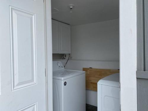 a small white laundry room with a washing machine at Steps To The Beach, Main Street and Pacific City - 2BR in Huntington Beach