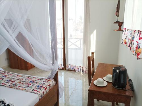 a bedroom with a bed and a table and a window at Zanzicrown in Nungwi