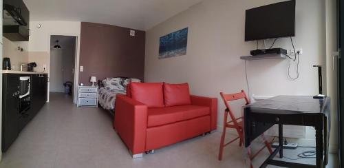 a living room with a red chair and a bed at Feel At Home Paris-Montreuil 500m Metro parking privé gratuit in Montreuil