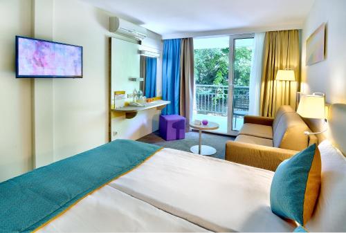 アルベナにあるHotel Ralitsa Aquaclub - Ultra All Inclusive plus Aquaparkのベッドとソファ付きのホテルルーム
