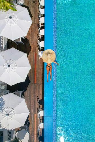 a man in a straw hat standing on the edge of a swimming pool at S Hotel Kingston in Kingston