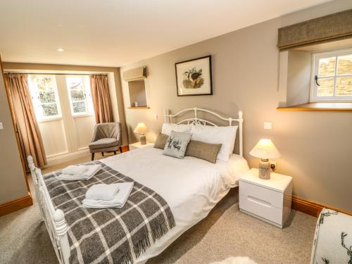 a bedroom with a white bed and a chair at The Barn in Bishop Auckland