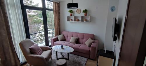 - un salon avec un canapé rose et une table dans l'établissement Apartman Monika Wind Resort, à Divčibare