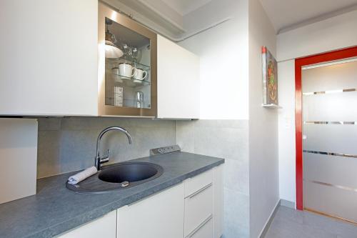 - une cuisine avec un évier et des placards blancs dans l'établissement Home A YourHostHelper, à Cannes