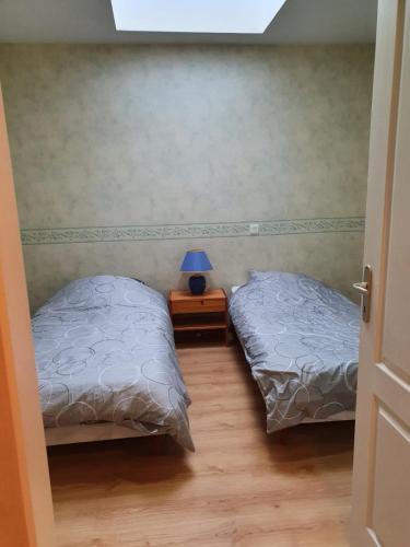 a bedroom with two beds and a table with a lamp at Le Saint-Hilaire in Saint-Hilaire-de-Brens