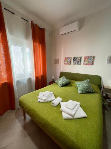 una camera da letto con un letto verde e asciugamani di Trastevere & Gianicolo Sweet Rest a Roma