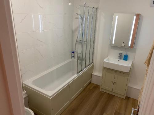 uma casa de banho branca com um chuveiro e um lavatório. em Adorable One-Bedroom Flat With Patio Garden. em Southwick