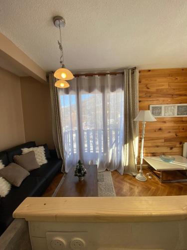 un salon avec un canapé et une grande fenêtre dans l'établissement Montclar Appart 4 à 6 places - terrasse vue panoramique - idéalement situé, à Montclar