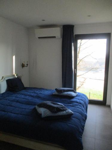um quarto com uma cama azul e uma grande janela em l'abri'gîte sous les arbres em Huy