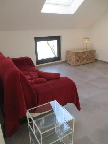 a living room with a red couch and a window at l'abri'gîte sous les arbres in Huy