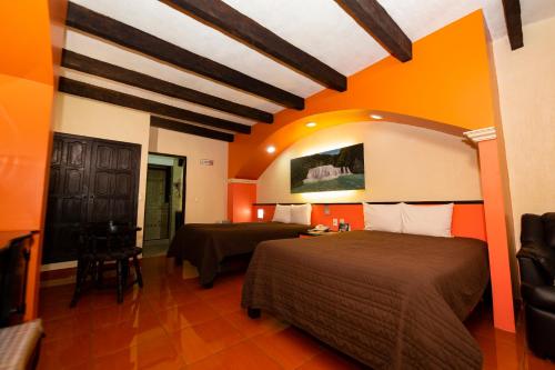 a bedroom with two beds and an orange wall at Hotel Catedral in San Cristóbal de Las Casas