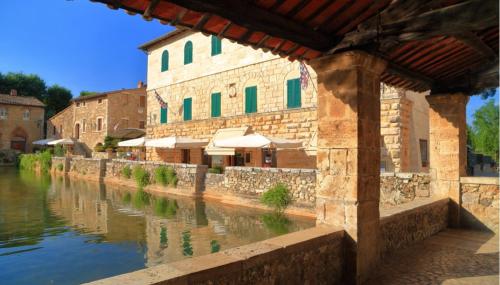 a building next to a river with a building at Camera La Margherita in San Quirico dʼOrcia