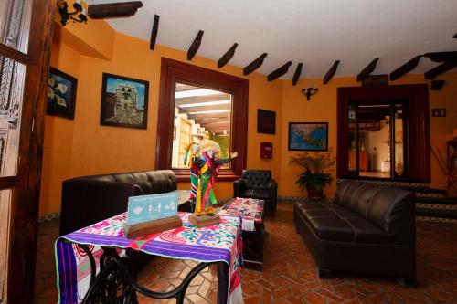 a woman standing in a living room with a table with a laptop at Hotel Catedral in San Cristóbal de Las Casas