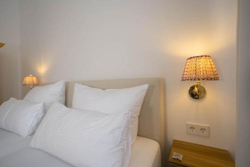 a bed with white pillows and two lamps on the wall at Logierhaus Austernfischer in Norderney