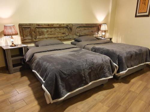 two beds in a room with two tables and two lamps at Azur Suites Hotel & Apartments in El Mîna