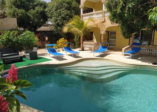 a swimming pool with blue chairs and a house at Résidence Sophia in Fatick