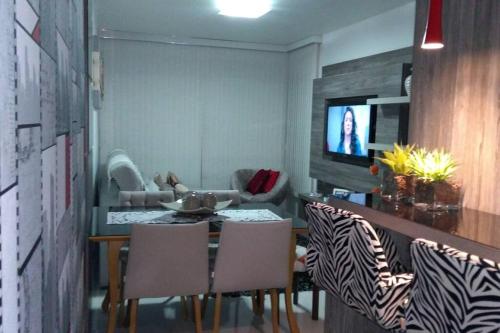 a dining room with a table and chairs and a television at Apartamento aconchegante em Bento Gonçalves, próximo ao vale dos vinhedos in Bento Gonçalves