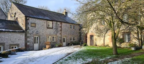 an old stone house with snow on the ground at Biggin Hall Country House Hotel in Hartington