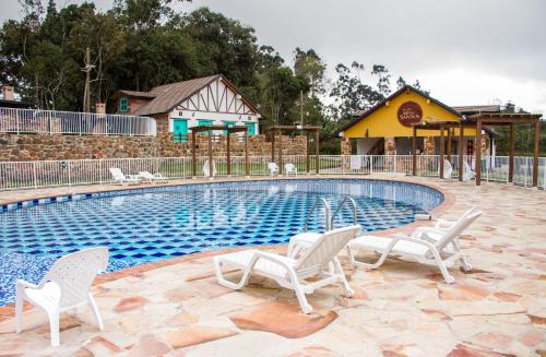 a swimming pool with white chairs and a playground at Hotel Mesa De Los Santos in Los Curos