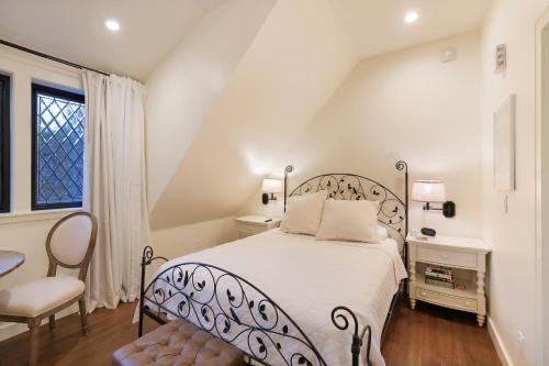 a white bedroom with a bed and a chair at New Tudor Cottage one block from Chico State and downtown with private garage in Chico