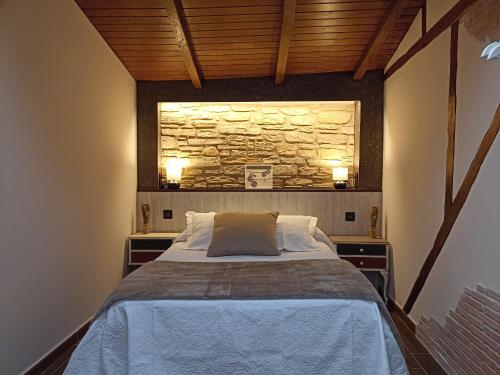 sypialnia z łóżkiem i kamienną ścianą w obiekcie El Cascanueces - Casa Rural w mieście Candelario