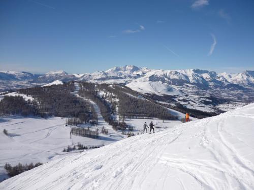 two people are skiing down a snow covered mountain at T3 coquet et lumineux aux pieds des pistes in Ancelle
