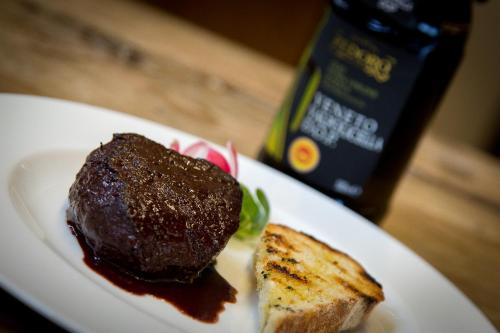 a white plate with a piece of steak and bread at Locanda Dell'Oleificio in Mezzane di Sotto