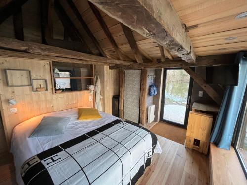 a bedroom with a bed in a room with wooden walls at La maison de l'O in Saint-Laurent-des-Hommes