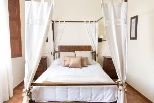 a bedroom with a canopy bed with white curtains at Casa Rural Aire in Fuente de Piedra