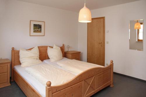 1 dormitorio con cama de madera con sábanas y almohadas blancas en Stephanie, en Sonthofen