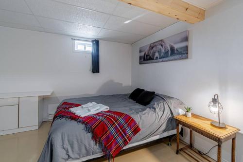 a bedroom with a bed and a table with a lamp at Spa, sauna et foyer : Le Phare de Baie-Saint-Paul in Baie-Saint-Paul