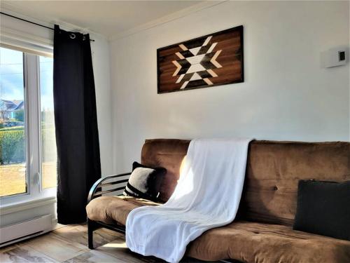 a couch with a blanket on it in a living room at Spa, sauna et foyer : Le Phare de Baie-Saint-Paul in Baie-Saint-Paul