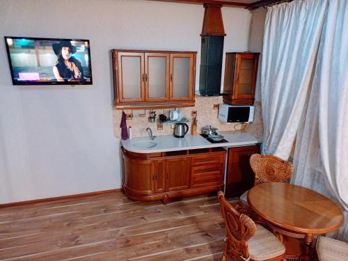 a kitchen with a table and a tv on the wall at Апартаменты в двух шагах от метро in Kharkiv