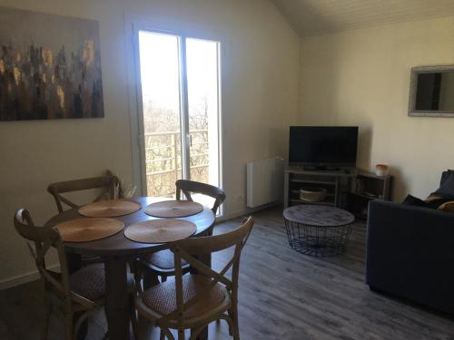 a living room with a table and chairs and a television at Les Gîtes du Lachat in Saint-Sylvestre