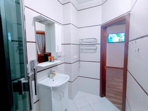 Baño blanco con lavabo y espejo en Апартаменты в двух шагах от метро en Járkov