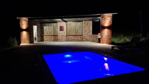 a blue pool in a yard at night at Forest Hill Country Lodge in Piet Retief
