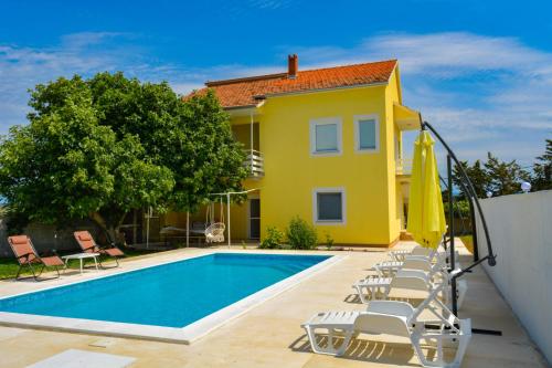 Casa amarilla con piscina y sillas en Villa Kutija, en Sveti Filip i Jakov