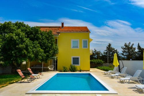 Casa amarilla con piscina y sillas en Villa Kutija, en Sveti Filip i Jakov