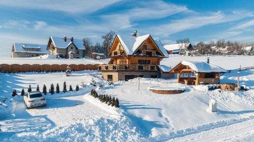 a house in the snow with a car in front at Domek w górach DeLuxe sauna,jacuzzi,basen,hot tub-Nowy Targ blisko Białka ,Zakopane in Nowy Targ