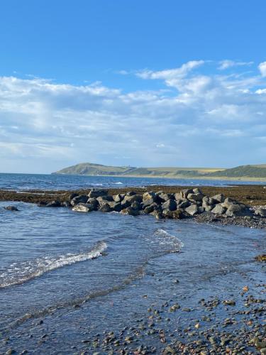 a group of rocks on a beach near the water at Unique Caravan with Outdoor Space Lodge in Ballantrae