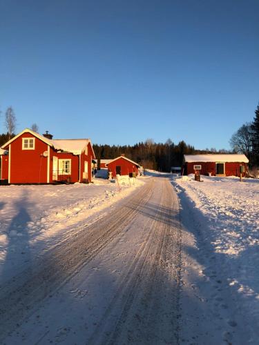 a snow covered road with a red house and snow at Trevlig stuga nära Hovfjället in Torsby