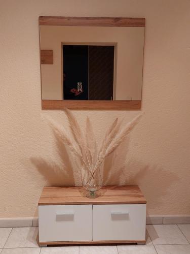 a mirror on a wall with a vase on a cabinet at Ferienwohnung Juco in Heddesheim