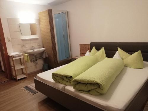 ein Schlafzimmer mit einem Bett mit gelben Kissen und einem Waschbecken in der Unterkunft Spisshof in Grins