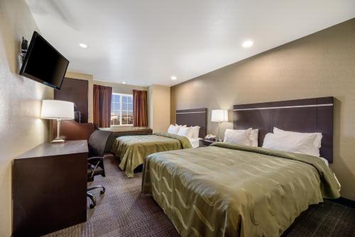 a hotel room with two beds and a flat screen tv at Quality Inn & Suites near NAS Fallon in Fallon
