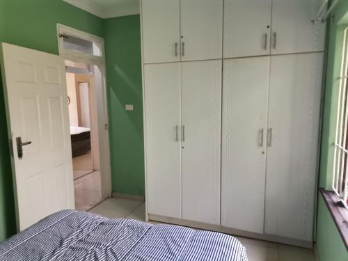 a bedroom with white cabinets and a green wall at Jackies Guest House in Durban