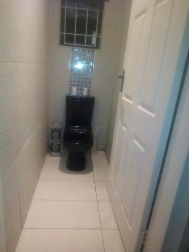 a bathroom with a black toilet and a door at Jackies Guest House in Durban