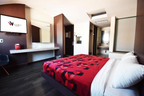 a hotel room with a bed with a red blanket at Hotel Via La Villa in Mexico City