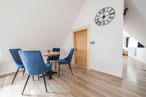 a dining room with blue chairs and a table and a clock at Atelier Jana Kasprowicza SAUNA&JACUZZI in Poronin