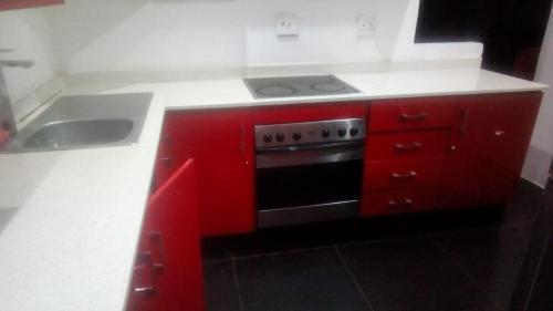 cocina roja con fogones y fregadero en Jackies Guest House, en Durban